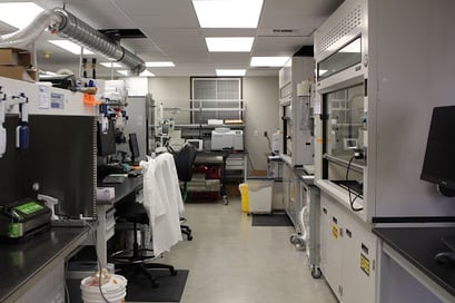 A view of the right side of the lab with computer work spaces, freeze driers, and ventilation hoods for working with material. 