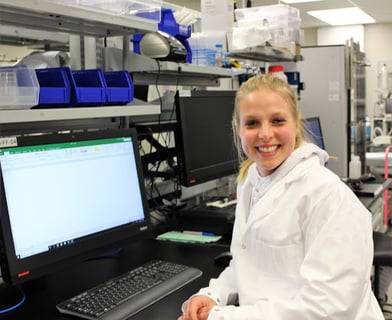 A picture of Kayla Owens, formulation scientist sitting in front of her computer in the lab. 