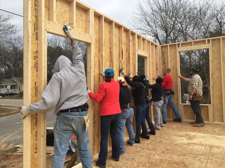Six AgBiomers help raise walls on a habitat for humanity home along with Habitat volunteers. 